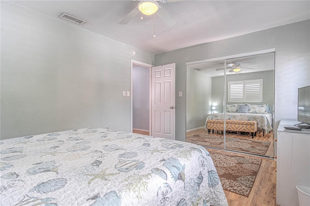 bedroom with ceiling fan, a closet, wood-type flooring, and a textured ceiling