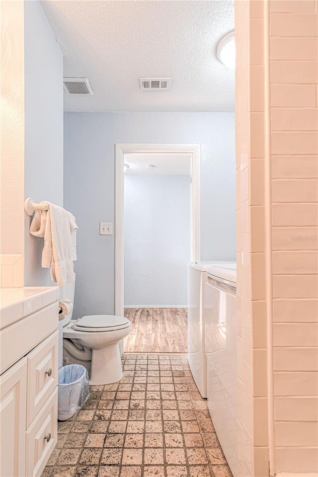 4017 Saxon Dr, New Smyrna Beach, FL 32169 - bathroom featuring independent washer and dryer, a textured ceiling, tile patterned floors, and vanity