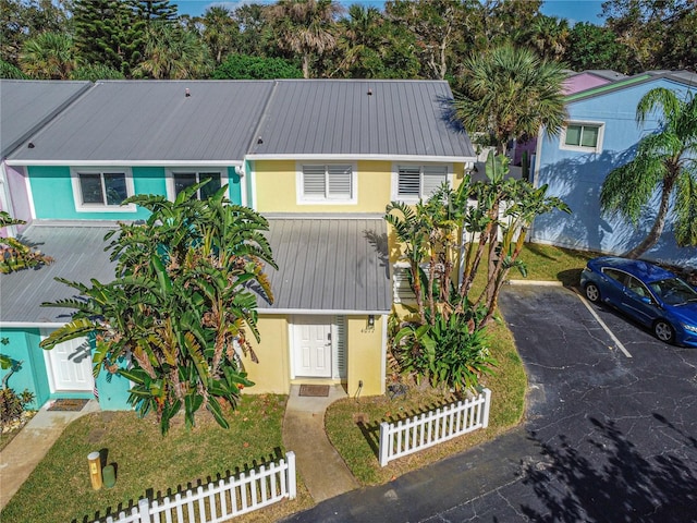 4017 Saxon Dr, New Smyrna Beach, FL 32169 - view of front of house with a metal roof, stucco siding, a fenced front yard, and uncovered parking