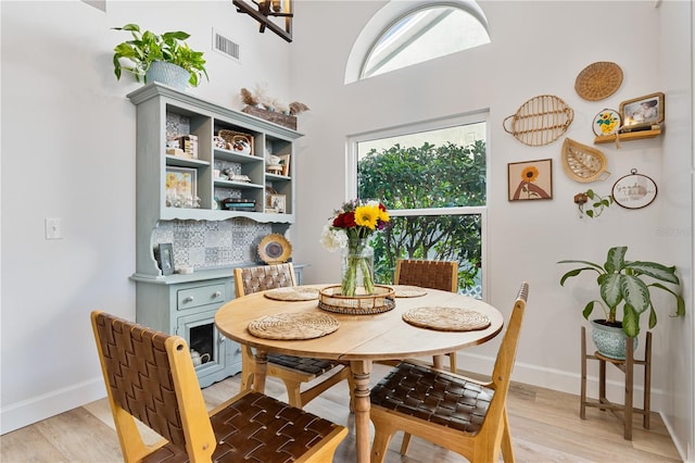 dining space with a towering ceiling and light hardwood / wood-style floors