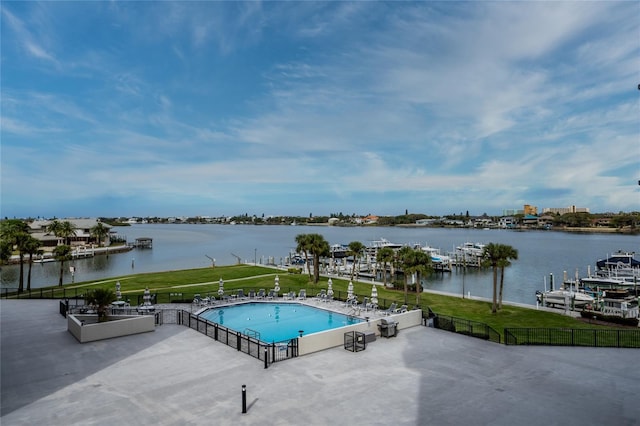 view of swimming pool featuring a lawn, a patio area, and a water view