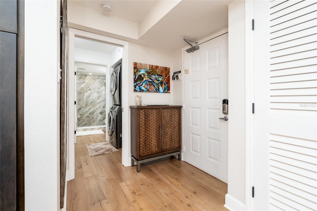 hall featuring stacked washer / dryer and light hardwood / wood-style flooring