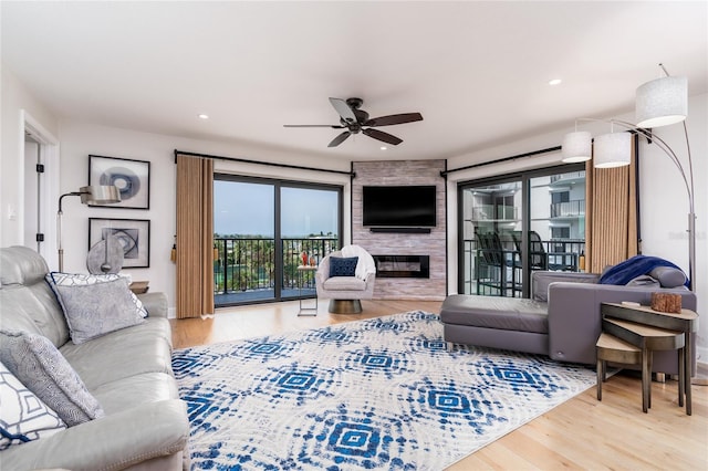 living room with hardwood / wood-style floors, a large fireplace, and ceiling fan