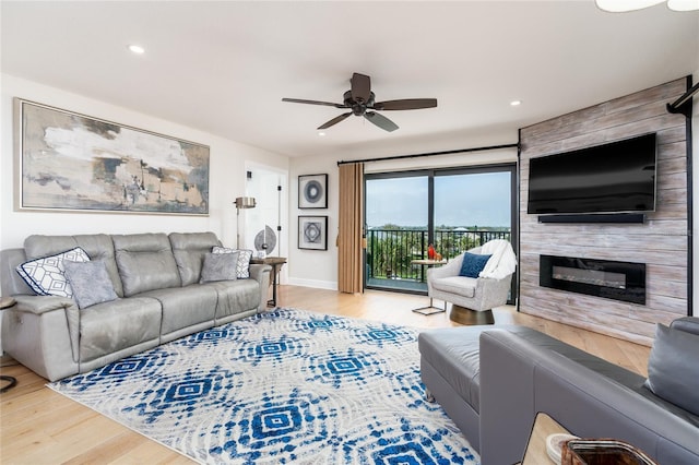 living room with a large fireplace, light hardwood / wood-style floors, and ceiling fan