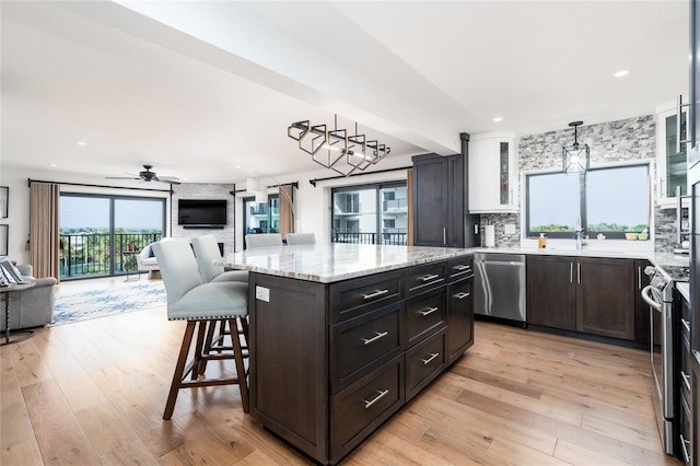 kitchen featuring a kitchen breakfast bar, pendant lighting, stainless steel appliances, and light hardwood / wood-style floors