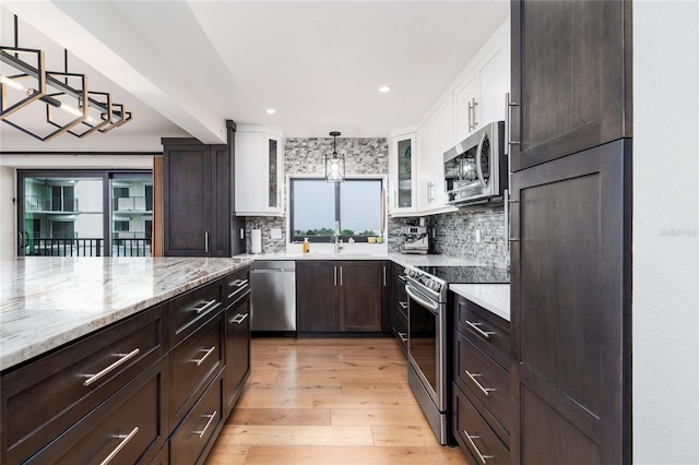 kitchen with white cabinets, light hardwood / wood-style floors, stainless steel appliances, and hanging light fixtures