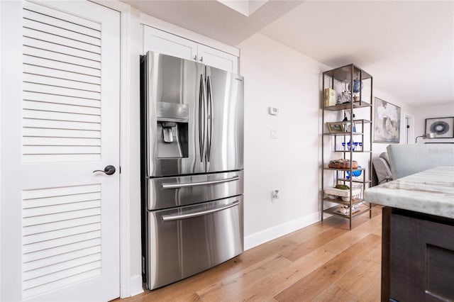 kitchen featuring white cabinets, stainless steel refrigerator with ice dispenser, and light hardwood / wood-style flooring