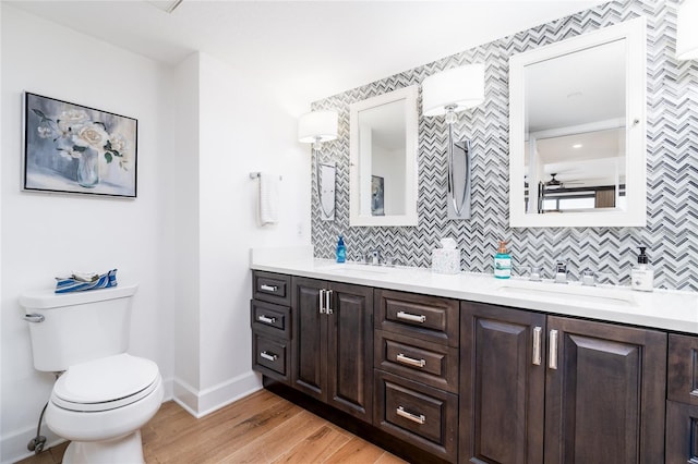 bathroom with tasteful backsplash, hardwood / wood-style floors, vanity, and toilet