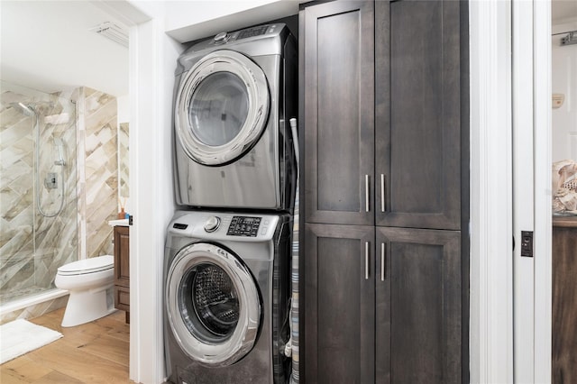 washroom featuring light hardwood / wood-style flooring, cabinets, and stacked washer and clothes dryer