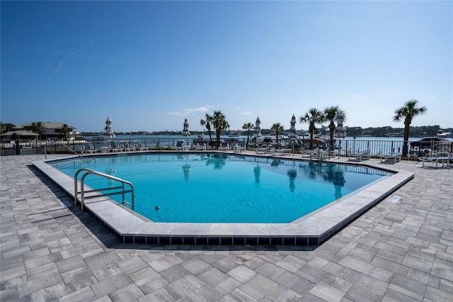 view of swimming pool with a patio area and a water view