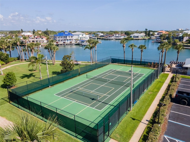 view of sport court with a water view and a yard