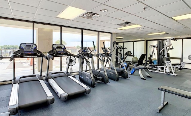 gym featuring a drop ceiling and a wall of windows