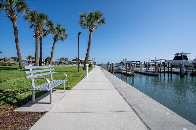 view of dock with a lawn and a water view