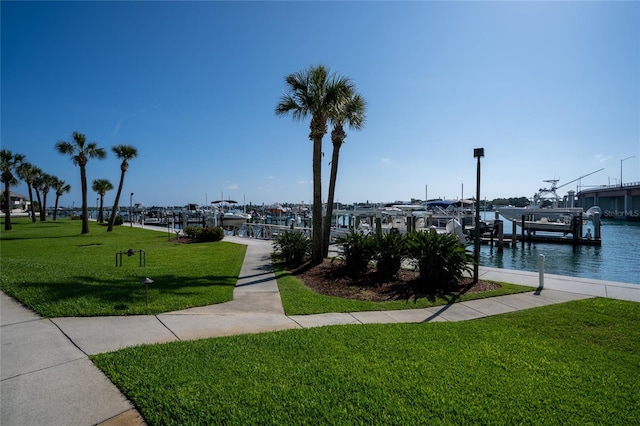 view of home's community with a water view, a lawn, and a boat dock