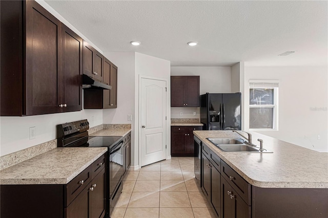 kitchen with light tile patterned flooring, sink, a kitchen island with sink, dark brown cabinetry, and black appliances