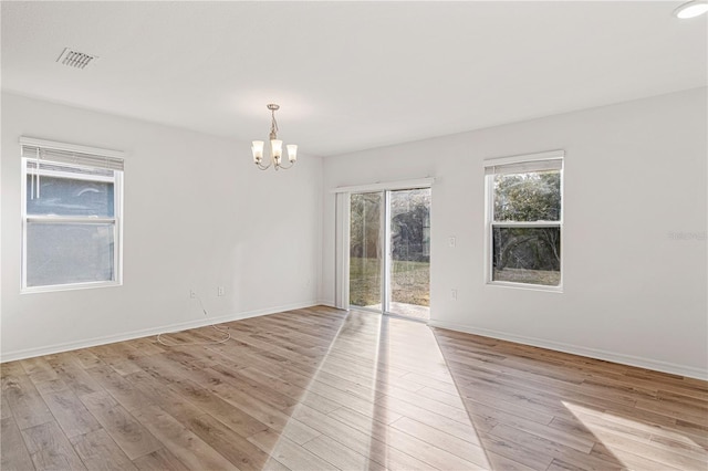 spare room with light hardwood / wood-style floors and a notable chandelier