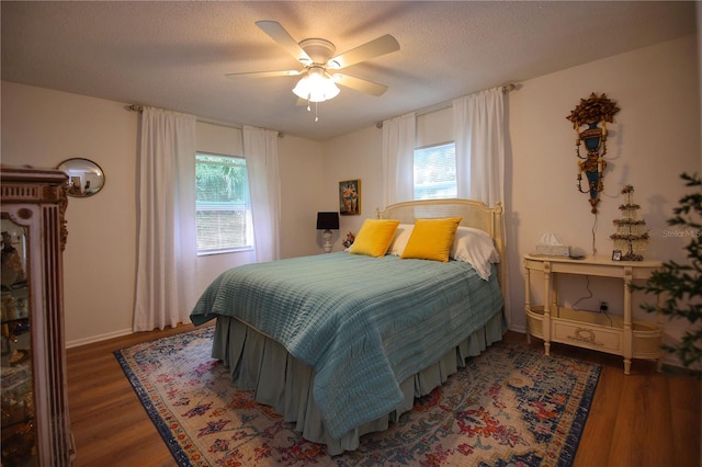 bedroom with multiple windows, ceiling fan, and dark wood-type flooring