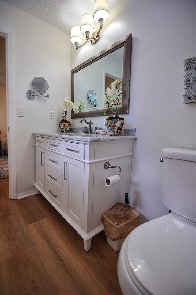 bathroom with hardwood / wood-style floors, vanity, a textured ceiling, and toilet