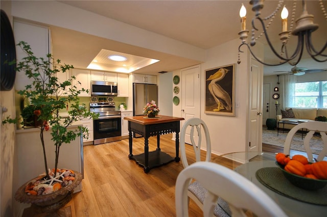 kitchen featuring white cabinets, a raised ceiling, light hardwood / wood-style flooring, ceiling fan, and appliances with stainless steel finishes