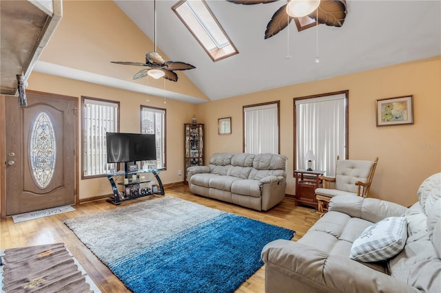 living room featuring ceiling fan, light wood-type flooring, high vaulted ceiling, and a skylight