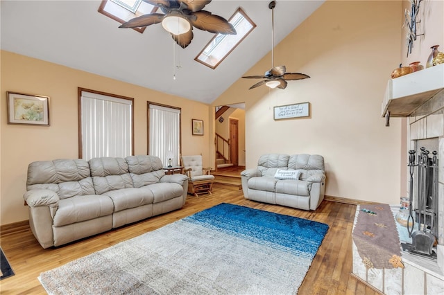 living room with a skylight, high vaulted ceiling, hardwood / wood-style flooring, and ceiling fan