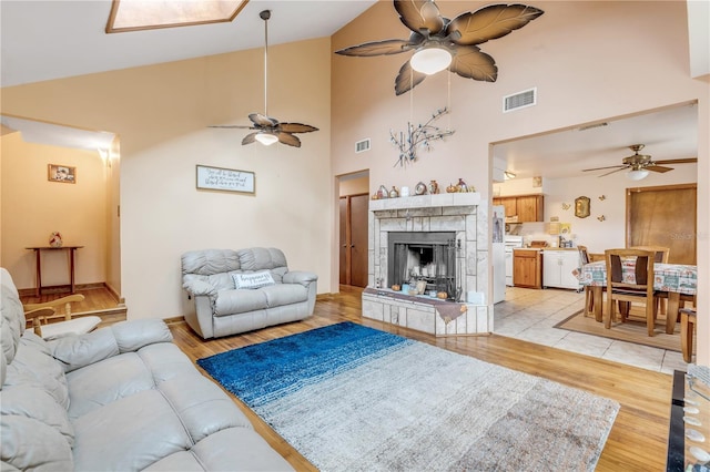 living room featuring a stone fireplace, light hardwood / wood-style flooring, and high vaulted ceiling