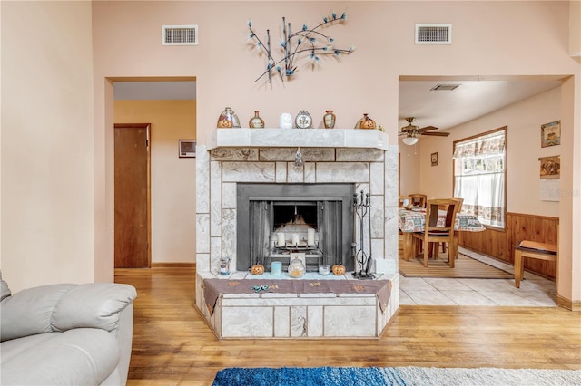 living room with a fireplace, light wood-type flooring, and ceiling fan