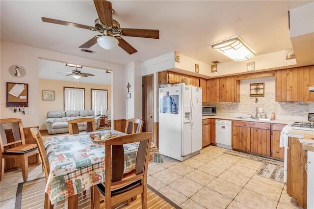 kitchen featuring decorative backsplash, sink, light tile patterned flooring, and white appliances