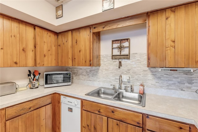 kitchen featuring white dishwasher, tasteful backsplash, and sink