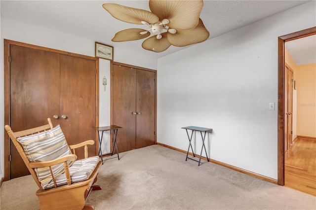 sitting room with a textured ceiling, light colored carpet, and ceiling fan