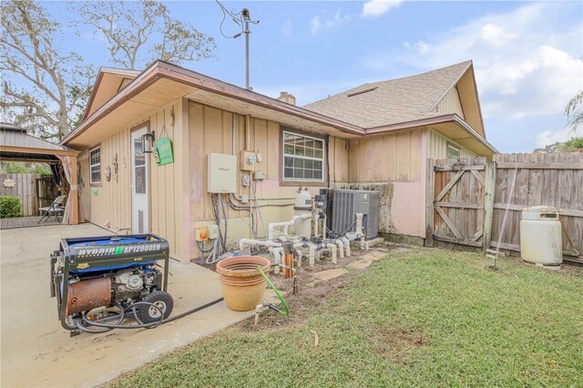 rear view of property featuring cooling unit, a patio area, and a yard