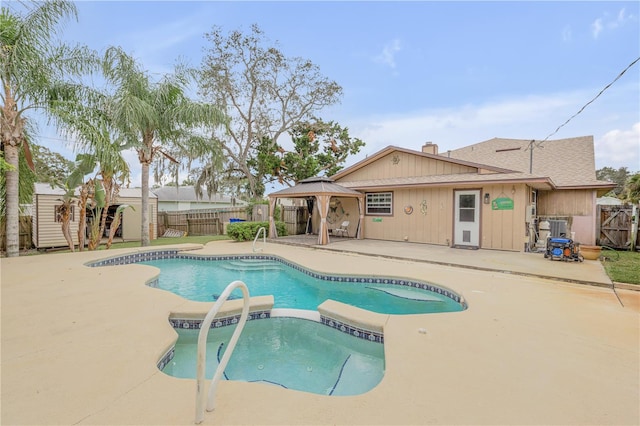 view of swimming pool with a gazebo, a patio area, an in ground hot tub, and a storage unit