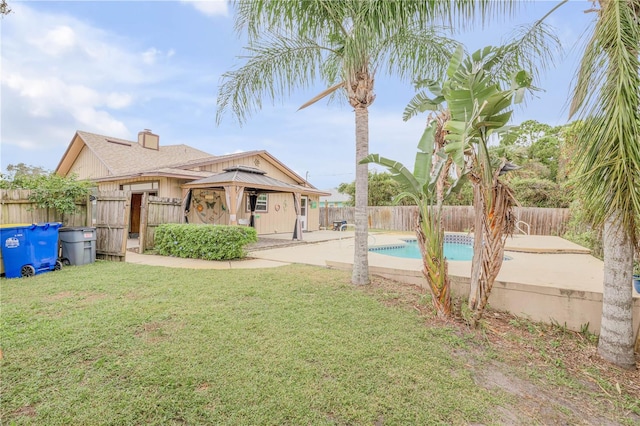 rear view of property featuring a gazebo, a fenced in pool, a patio, and a lawn