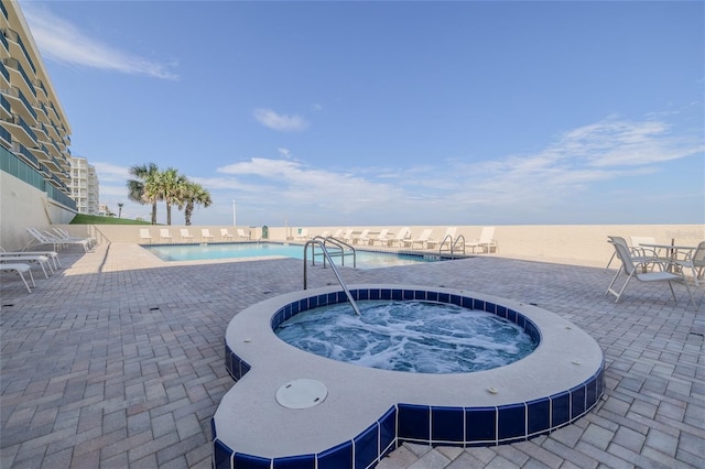 view of pool featuring a community hot tub, a water view, and a patio area