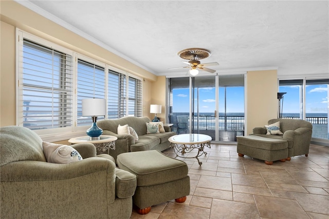 living room with ornamental molding, a water view, a wealth of natural light, and a wall of windows