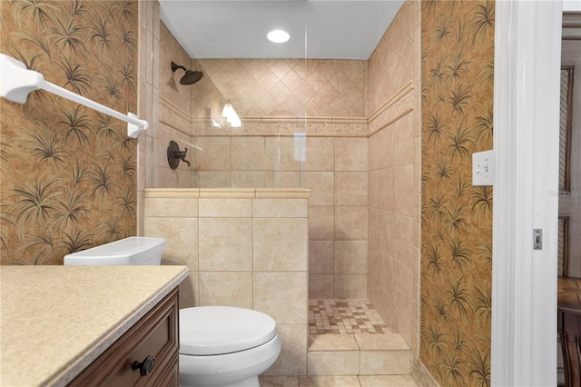 bathroom with vanity, toilet, and tiled shower