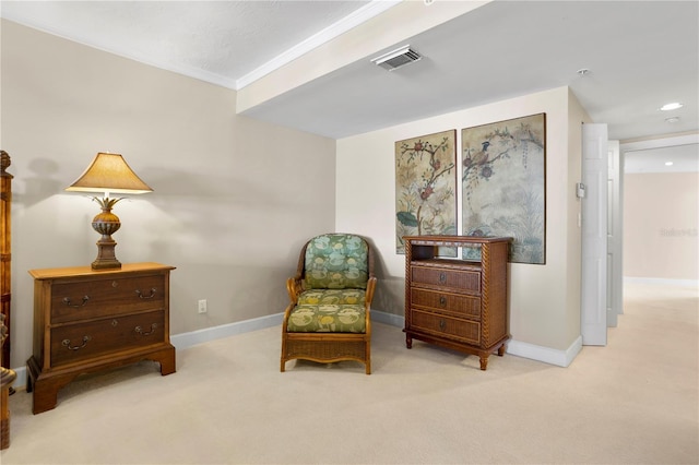 sitting room with ornamental molding and light colored carpet