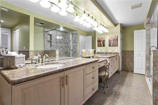 bathroom featuring a shower with door, vanity, tile walls, and tile patterned floors