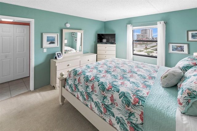 bedroom featuring light carpet, a closet, and a textured ceiling