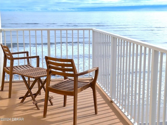 balcony featuring a view of the beach and a water view