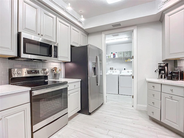 kitchen featuring tasteful backsplash, appliances with stainless steel finishes, separate washer and dryer, and light wood-type flooring