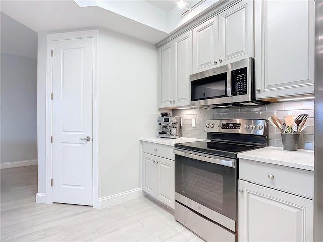 kitchen featuring appliances with stainless steel finishes, backsplash, and light hardwood / wood-style floors