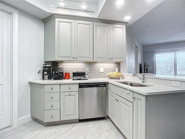 kitchen with sink, light hardwood / wood-style flooring, dishwasher, gray cabinetry, and decorative backsplash