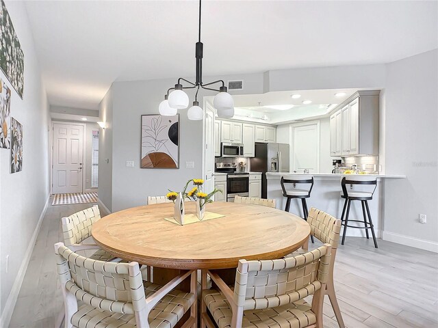 dining area with a chandelier and light wood-type flooring