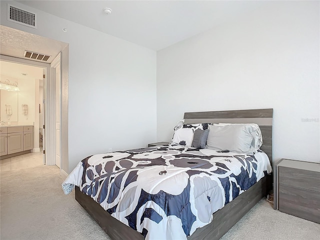 bedroom with light colored carpet and ensuite bathroom