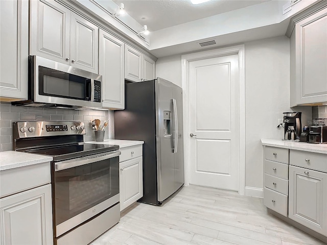 kitchen with track lighting, appliances with stainless steel finishes, and decorative backsplash