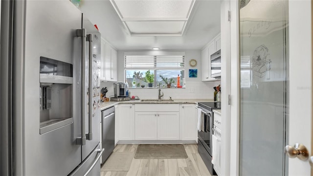 4411 Sea Mist Ct Unit 275, New Smyrna Beach, FL 32169 - kitchen featuring appliances with stainless steel finishes, light wood finished floors, white cabinetry, backsplash, and light stone countertops