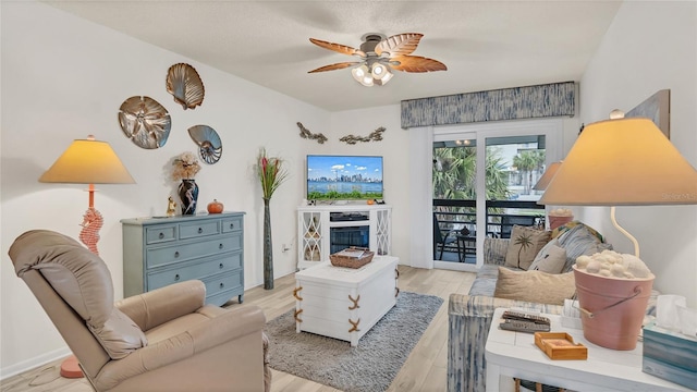 4411 Sea Mist Ct Unit 275, New Smyrna Beach, FL 32169 - living room featuring a ceiling fan, light wood-style flooring, and a glass covered fireplace
