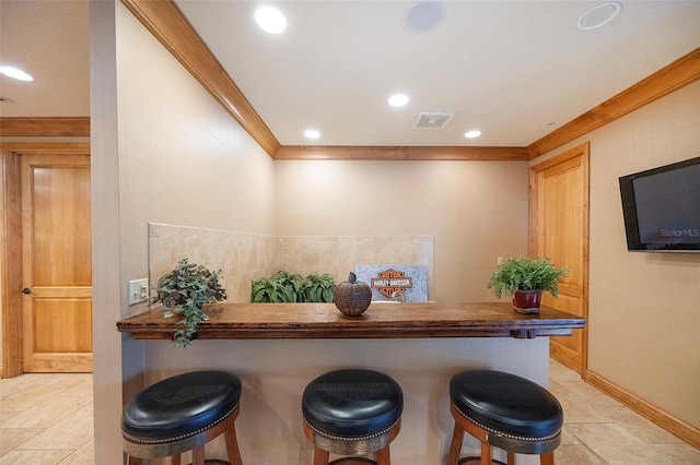 kitchen featuring a kitchen bar, kitchen peninsula, wood counters, and ornamental molding