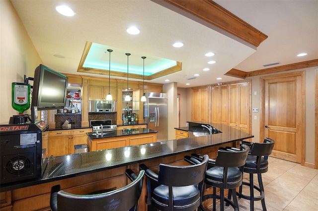 kitchen with appliances with stainless steel finishes, backsplash, a raised ceiling, sink, and decorative light fixtures